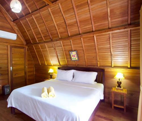 una camera da letto con un letto bianco con due asciugamani di Nusa Penida Pudak Nature Bungalow a Nusa Penida