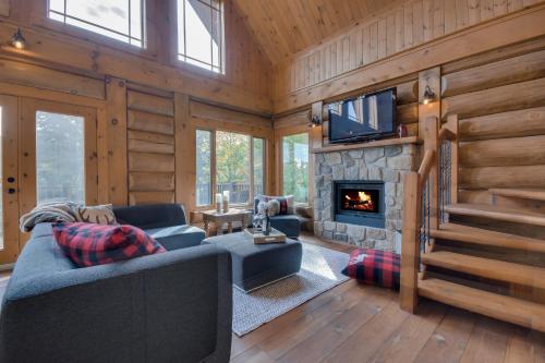 ein Wohnzimmer mit einem Sofa und einem Kamin in der Unterkunft Log Cabin Home with Lake and Mountain view by Reserver.ca in Sainte-Adèle