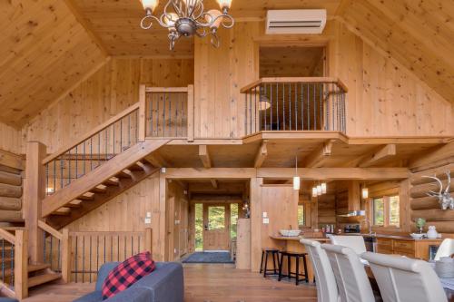 eine Blockhütte mit einer Wendeltreppe im Wohnzimmer in der Unterkunft Log Cabin Home with Lake and Mountain view by Reserver.ca in Sainte-Adèle