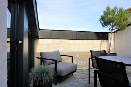 un patio con una silla, una mesa y un árbol en Hôtel Cardinal Bordeaux Centre, en Burdeos