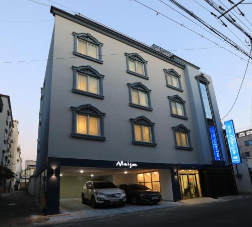 een gebouw met twee auto's ervoor geparkeerd bij Maison Mini Hotel in Gyeongju