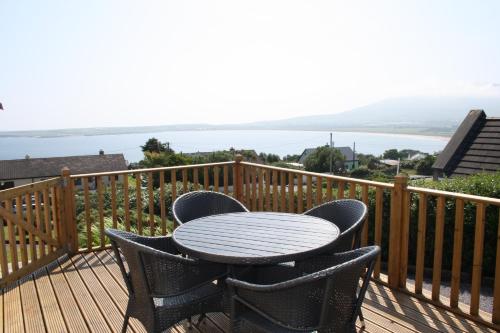 Ard na Carraige, Ventry Holiday Home في دينغل: طاولة وكراسي على سطح مطل على الماء