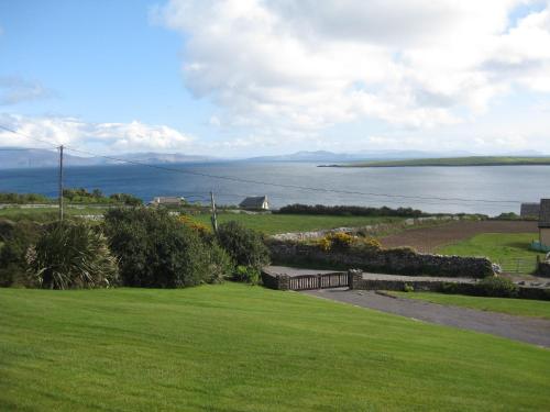 Ard na Carraige, Ventry Holiday Home في دينغل: إطلالة على المحيط من حديقة مع مقعد