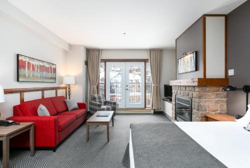 ein Wohnzimmer mit einem roten Sofa und einem Kamin in der Unterkunft Tour des Voyageurs in Mont-Tremblant