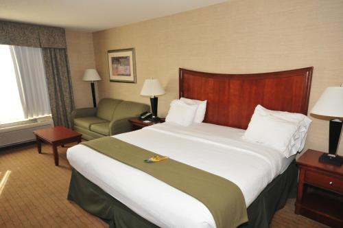 シャンペーンにあるHoliday Inn Express Hotel & Suites Urbana-Champaign-U of I Area, an IHG Hotelの大きなベッドと椅子が備わるホテルルームです。