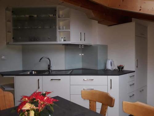 a kitchen with white cabinets and a sink and a table at Apartment Suliva in Santa Cristina in Val Gardena