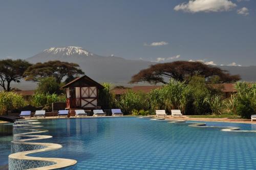 une piscine avec des chaises et une montagne en arrière-plan dans l'établissement Kilima Safari Camp, à Amboseli