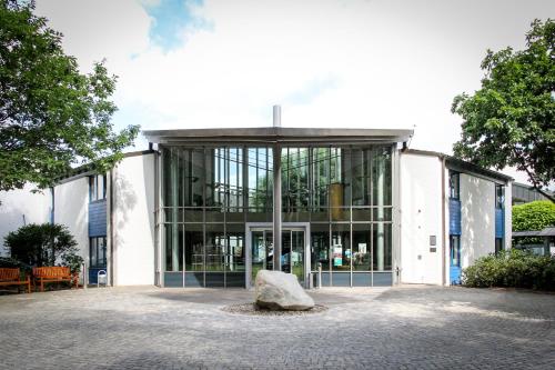 un grand bâtiment en verre avec un grand rocher devant dans l'établissement Hotel Park Soltau, à Soltau