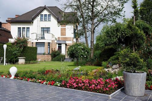 uma casa com um jardim com flores em frente em Hotel La Roseraie em Wemmel