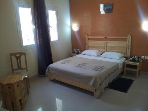 a bedroom with a large bed and two windows at Résidence El Arich in Tozeur