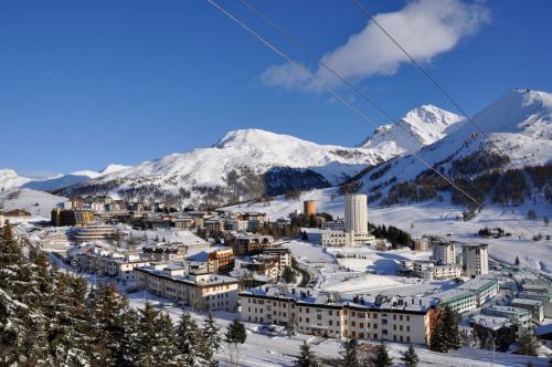 塞斯特雷Hotel Savoy Sestriere的雪中城市,以山为背景