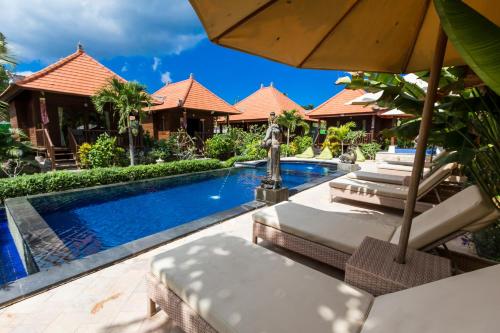 una piscina del complejo con sillas y sombrilla en Dream Beach Cottages, en Nusa Lembongan