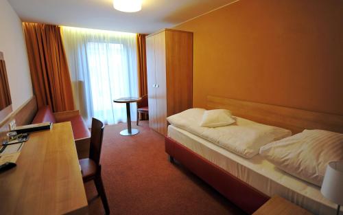 een kleine hotelkamer met een bed en een bureau bij Hotel Club in Kežmarok