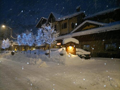 un patio cubierto de nieve con árboles y luces en Hotel Dei Camosci, en Courmayeur