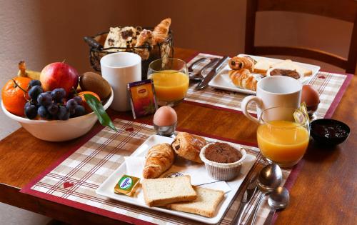 - une table de petit-déjeuner avec un plateau de produits pour le petit-déjeuner et du jus d'orange dans l'établissement The Originals Boutique, Hôtel La Ferme du Pape, Eguisheim, à Eguisheim