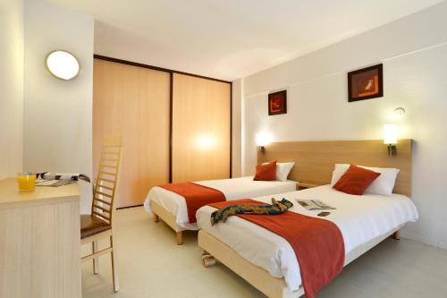 a hotel room with two beds and a desk at Vacancéole - Les Demeures Champenoises in Épernay