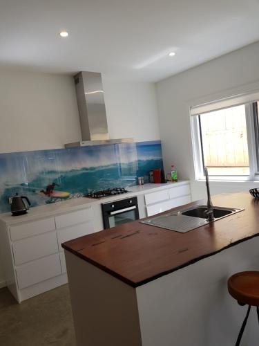 cocina con armarios blancos y encimera de madera en Zeally Bay Stay Deep Ocean, en Torquay