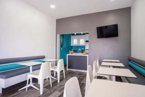 une salle à manger avec des tables, des chaises et une télévision dans l'établissement Hotel Cap Sud, à Saint-Pierre