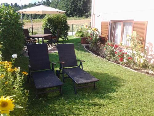 eine Gruppe Stühle und ein Regenschirm auf einem Hof in der Unterkunft Ferienwohnung-Hajek in Sankt Ruprecht an der Raab