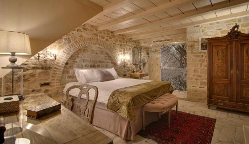 een slaapkamer met een bed en een stenen muur bij KAMARES Historic Boutique Hotel & Spa in Ioannina