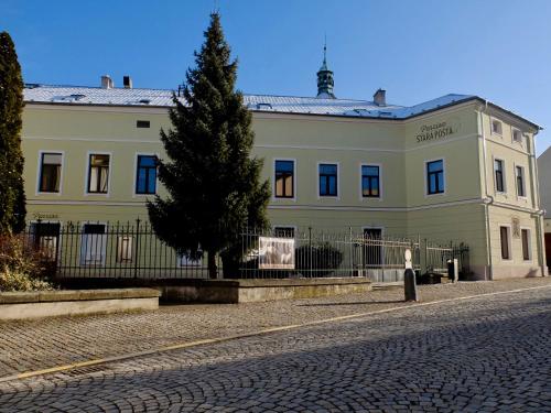 un gran edificio blanco con un árbol delante en Penzion Stará pošta, en Frýdek-Místek