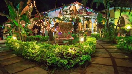 um jardim iluminado à noite com luzes de Natal em Shivers Oasis Luxury Boutique Resort em Candolim