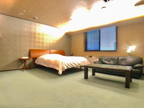 1 dormitorio con cama, sofá y banco en Hotel Ritz Koshien, en Nishinomiya