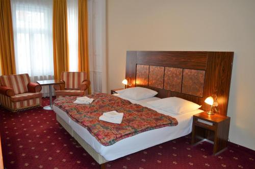 ein Hotelzimmer mit einem großen Bett und zwei Stühlen in der Unterkunft Hotel Palacky in Karlsbad