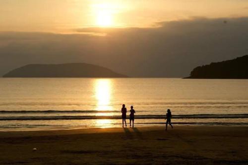 3 personnes debout sur la plage au coucher du soleil dans l'établissement Chale Cantinho Albamar, à Ubatuba