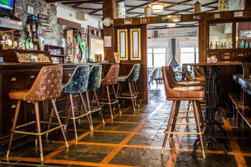 a bar with a bunch of stools in a room at Killarney Heights Hotel in Killarney