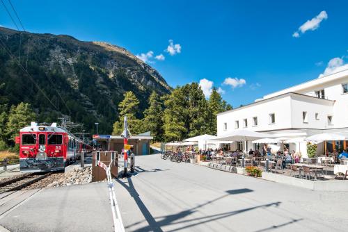 un tren rojo entrando en una estación de tren con gente esperando en Hotel Morteratsch, en Pontresina