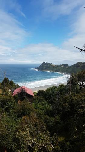 a view of a beach with a house and the ocean at Cabañas Emma Maicolpue in Osorno