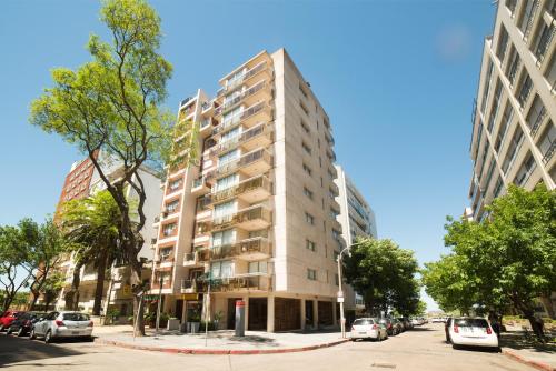 un edificio alto in una strada di città con auto parcheggiate di 27 Suites Hotel a Montevideo