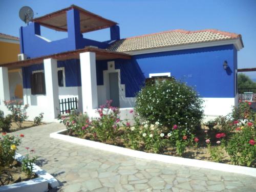 ein blau-weißes Haus mit Blumen davor in der Unterkunft Ilis Villas in Kyllini