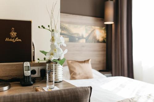 um quarto de hotel com uma cama e uma mesa com um telefone em Hotel Sion em Colónia