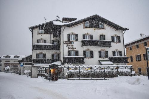 duży biały budynek ze śniegiem w obiekcie Hotel Stella Alpina w mieście Fai della Paganella