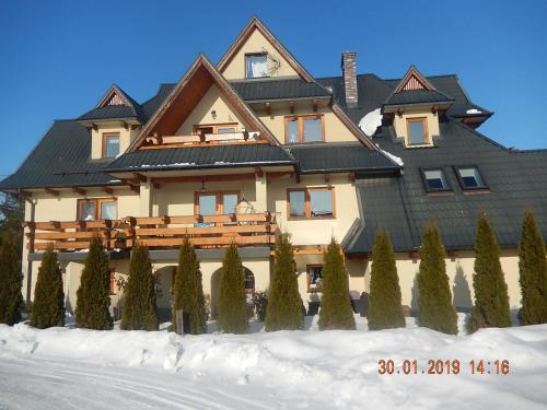 una grande casa con un tetto nero nella neve di U Hanki a Biały Dunajec