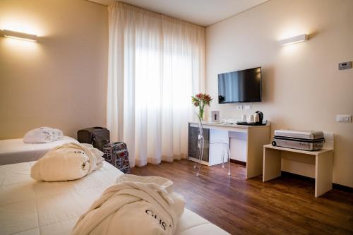 Cette chambre comprend deux lits, un bureau et une télévision. dans l'établissement Astoria Palace Hotel, à Palerme