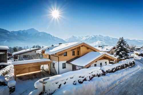 ein Haus voller Schnee mit der Sonne am Himmel in der Unterkunft Apartment 5 Peaks in Zell am See