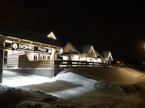 eine Holzhütte im Schnee in der Nacht in der Unterkunft Domki Pasja II 2,5 km do wyciągu naciarskiego Czorsztyn Ski in Kluszkowce