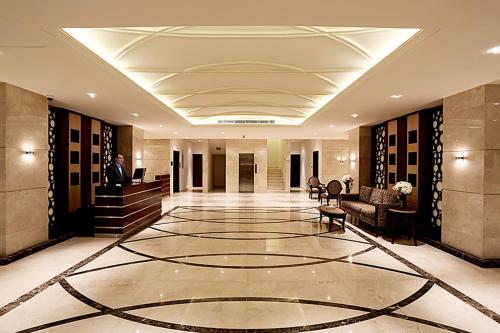 lobby z mężczyzną siedzącym przy biurku w budynku w obiekcie Aswar Hotel Suites w mieście Al-Chubar