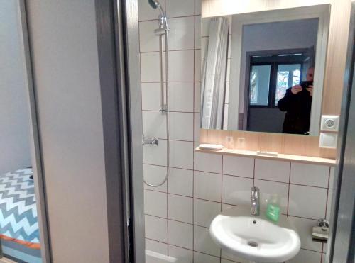 un uomo che scatta una foto di un bagno con lavandino di Park Rooms a Dugo Selo