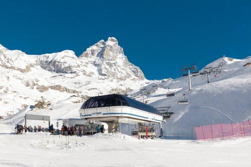 un bâtiment au sommet d'une montagne enneigée dans l'établissement HelloChalet - Maison Rêve Blanc - Ski to door with Matterhorn view, à Breuil-Cervinia