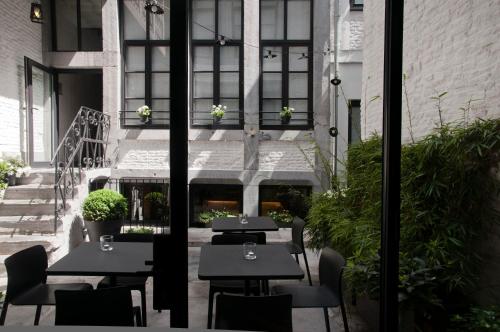 a patio with tables and chairs in a building at Hotel Neuvice in Liège