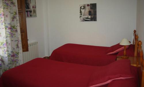 two beds in a bedroom with red sheets at Hostal Rural Las Terrazas de la Alpujarra in Bubión