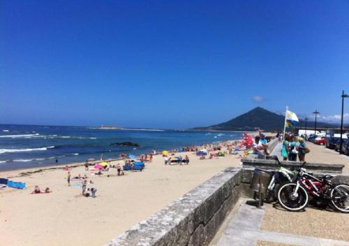 un groupe de personnes sur une plage avec l'océan dans l'établissement Trajadinha FêloHouse, à Caminha