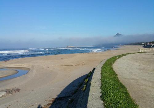 une plage de sable au bord de l'océan avec une clôture dans l'établissement Trajadinha FêloHouse, à Caminha