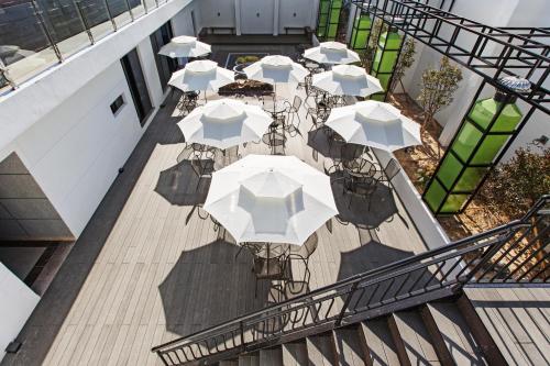 een balkon met uitzicht op tafels en parasols bij Notte La Mia Hotel in Busan