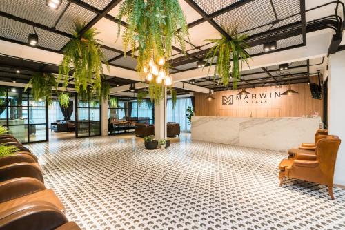 a lobby with chairs and potted plants at Marwin Villa in Bangkok