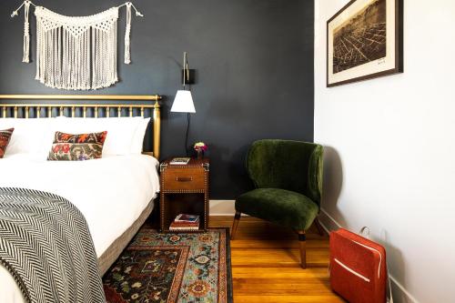 um quarto com uma cama e uma cadeira verde em The Armstrong Hotel em Fort Collins